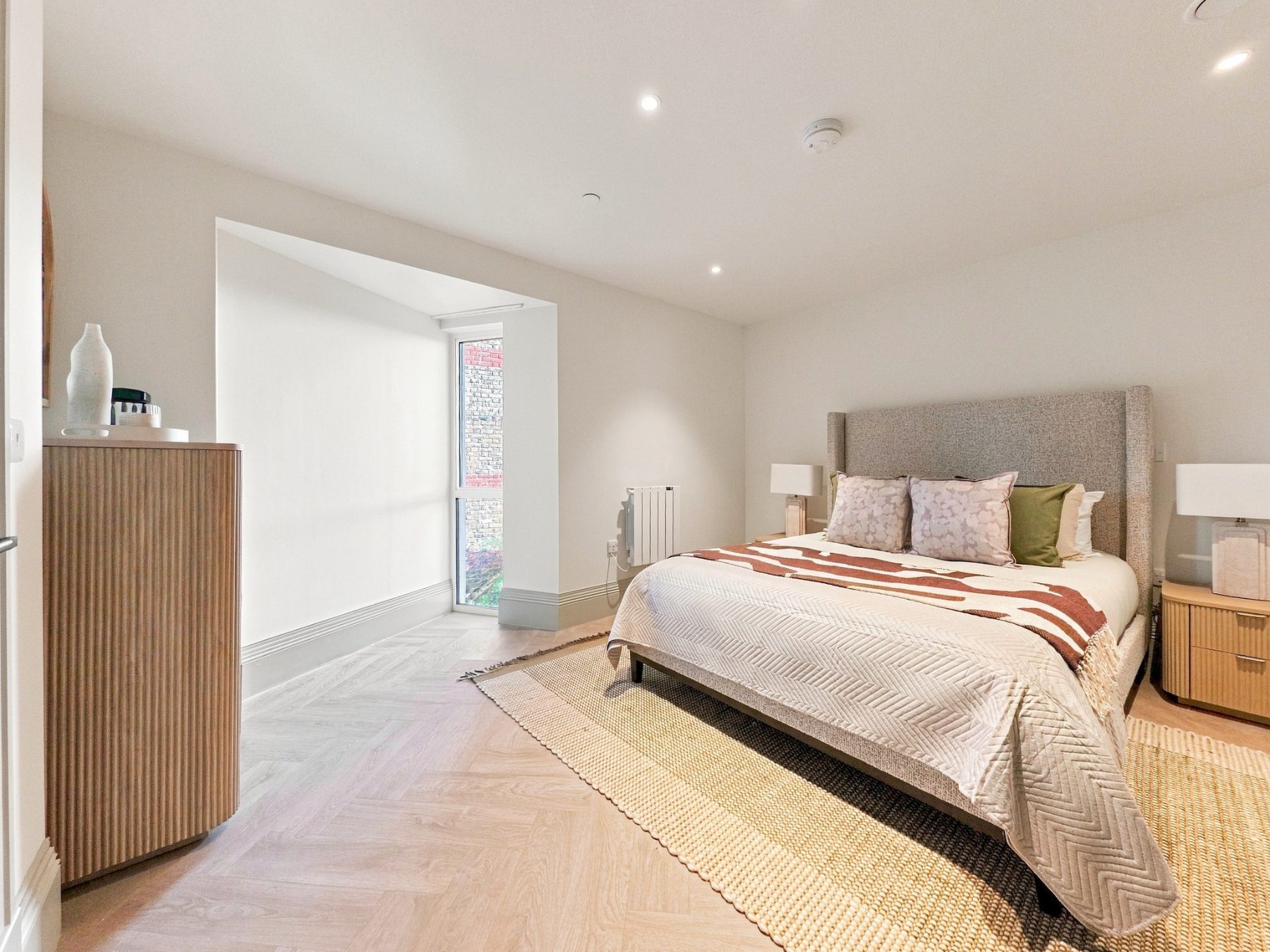 Double bedroom with a bay window, herringbone style floor and soft neutral styling