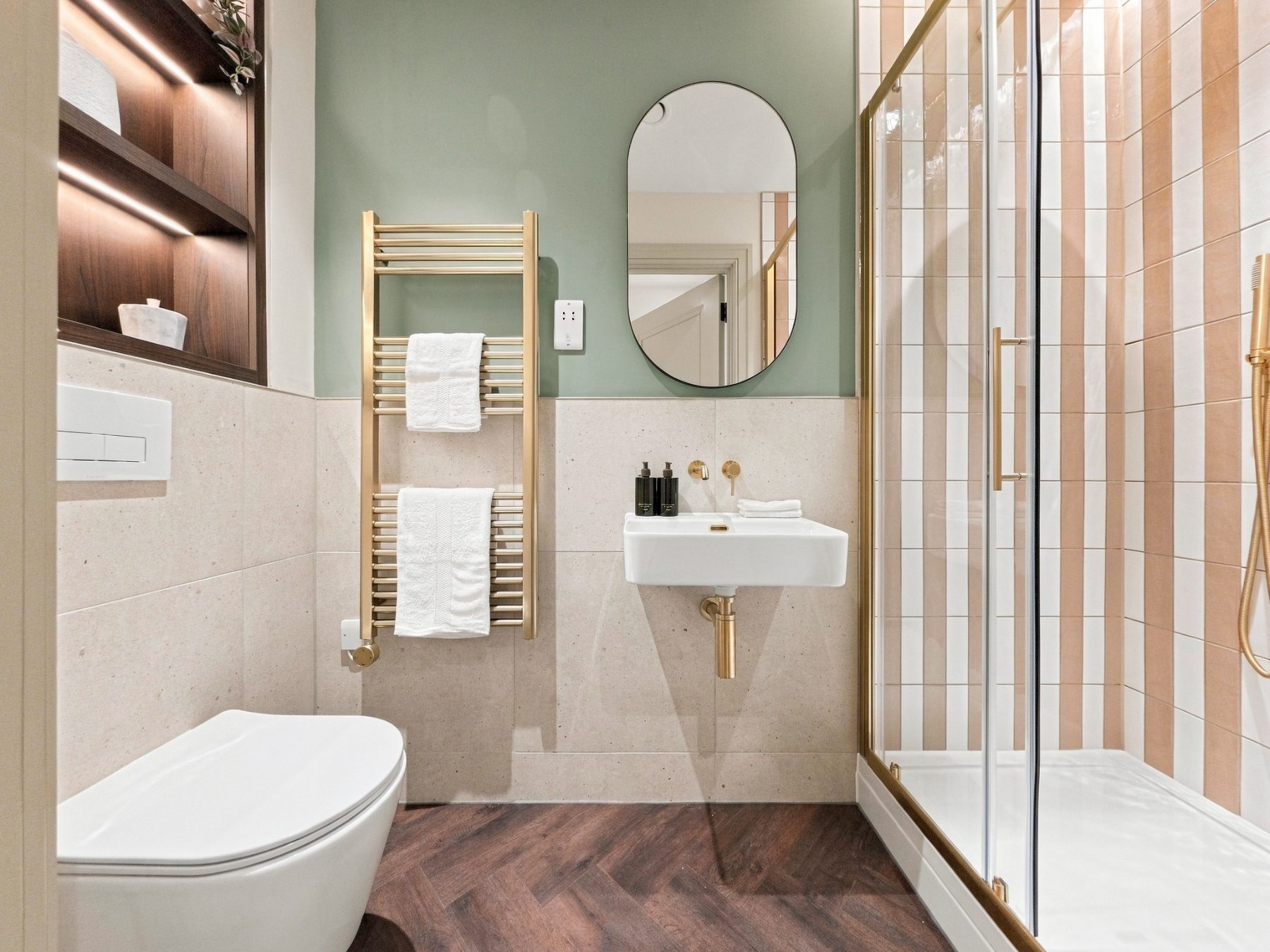 Shower room with sage green wall, brass towel rail and wall hung WC