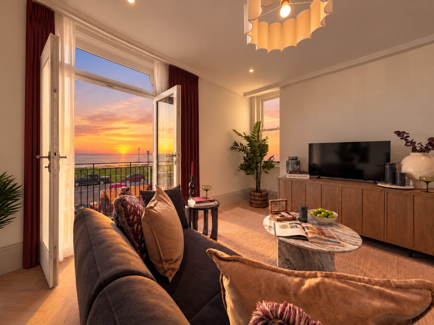 Living room at sunset with doors open to a balcony overlooking the bay